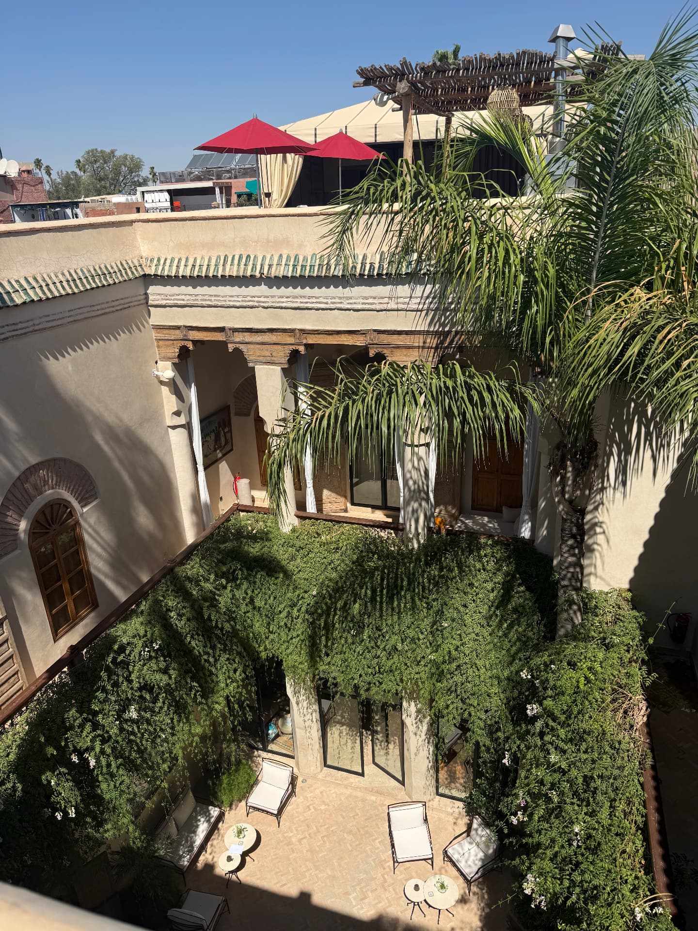 The courtyard of our riad, with palm, vines and red umbrellas overhead